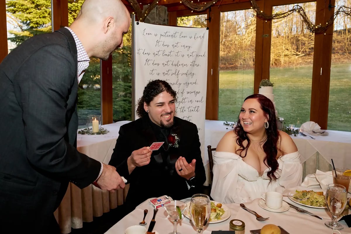 Wedding magician performs a trick for a smiling bride.